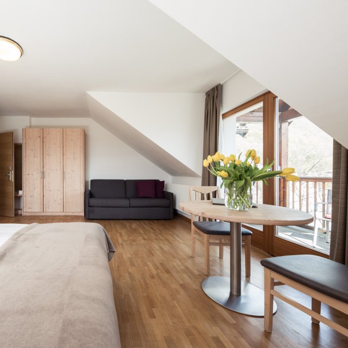 Helles Zimmer im Hotel Masatsch mit rundem Tisch und frischen Blumen